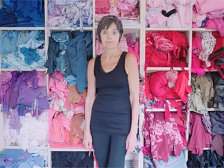 ArtistLindaFriedmanSchmidtinfrontofthewallofdiscardedclothinginherstudio KelseyBennett